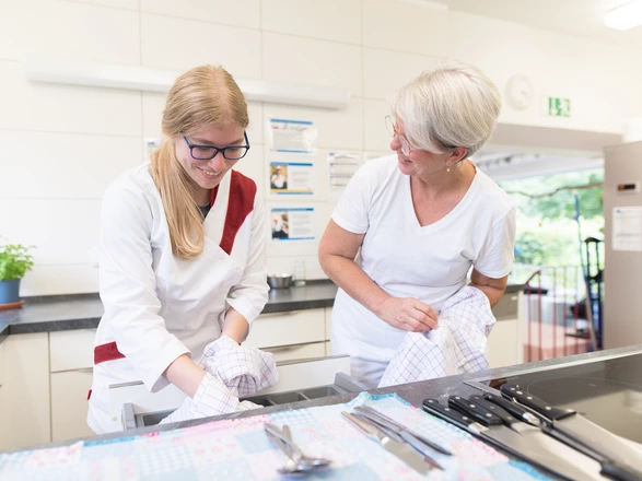 Auszubildende und Ausbilderin polieren Besteck