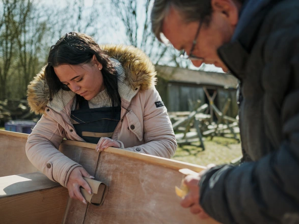 Zwei Lehrkräfte schleifen eine Holzkonstruktion an